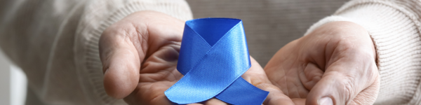 Foto von 2 Händen, die eine blaue Schleife als Symbol für Darmkrebs halten