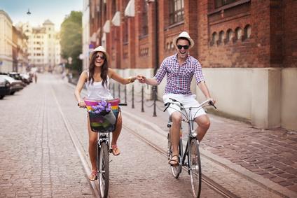 Männer- und Frauen-Produkte: Junges Paar fährt Hand in Hand Fahrrad.