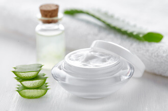 Tiegel mit Creme zur Hautpflege neben Aloe vera: Hautpflegeprodukte gibt es für jeden Hauttyp.