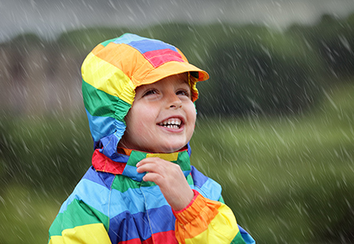 Lachendes Kind im Regen hat Dank des Kindervital® Tonikums von Salus® ein gutes Immunsystem.